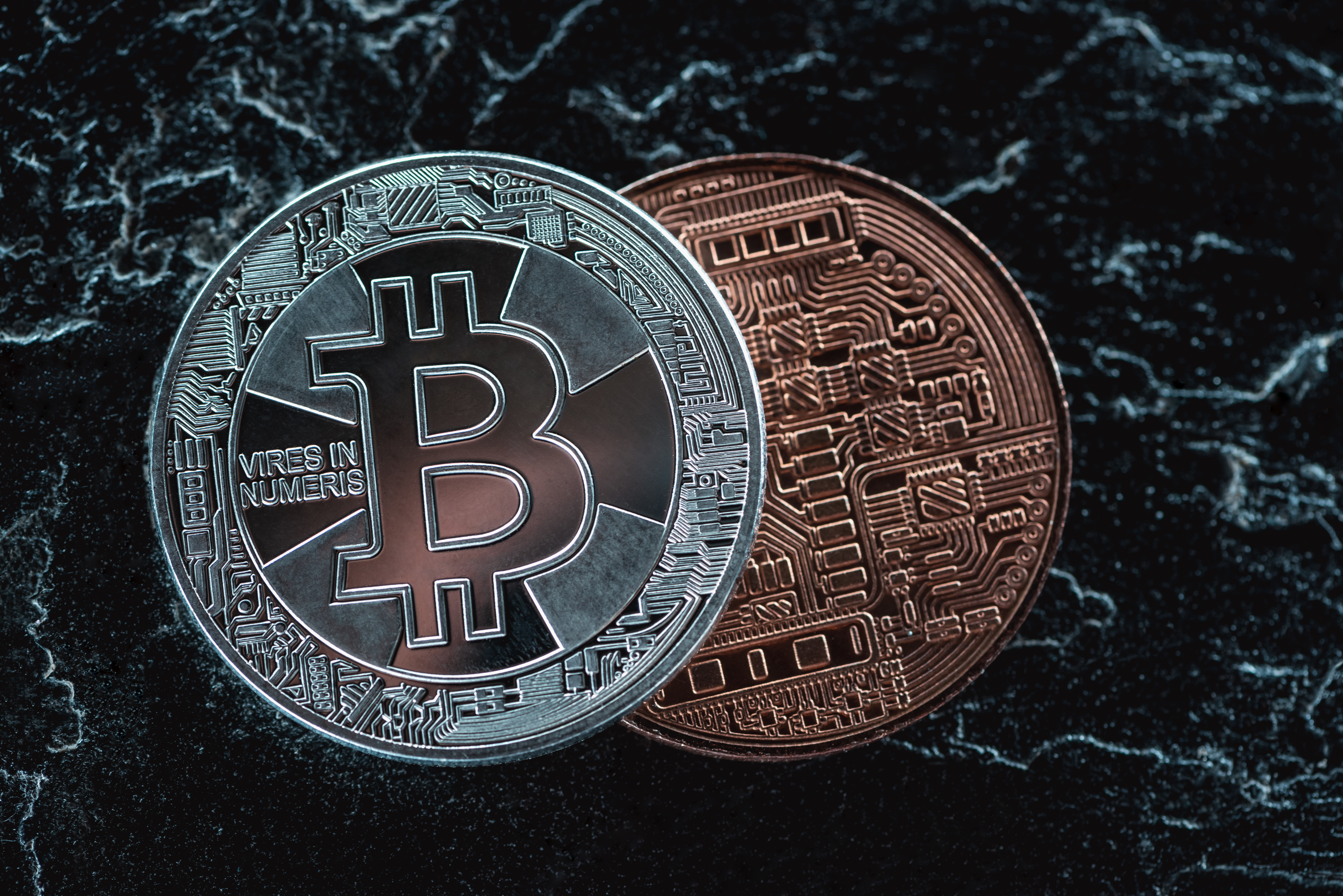 close up view of arranged silver and bronze bitcoins on dark marble surface