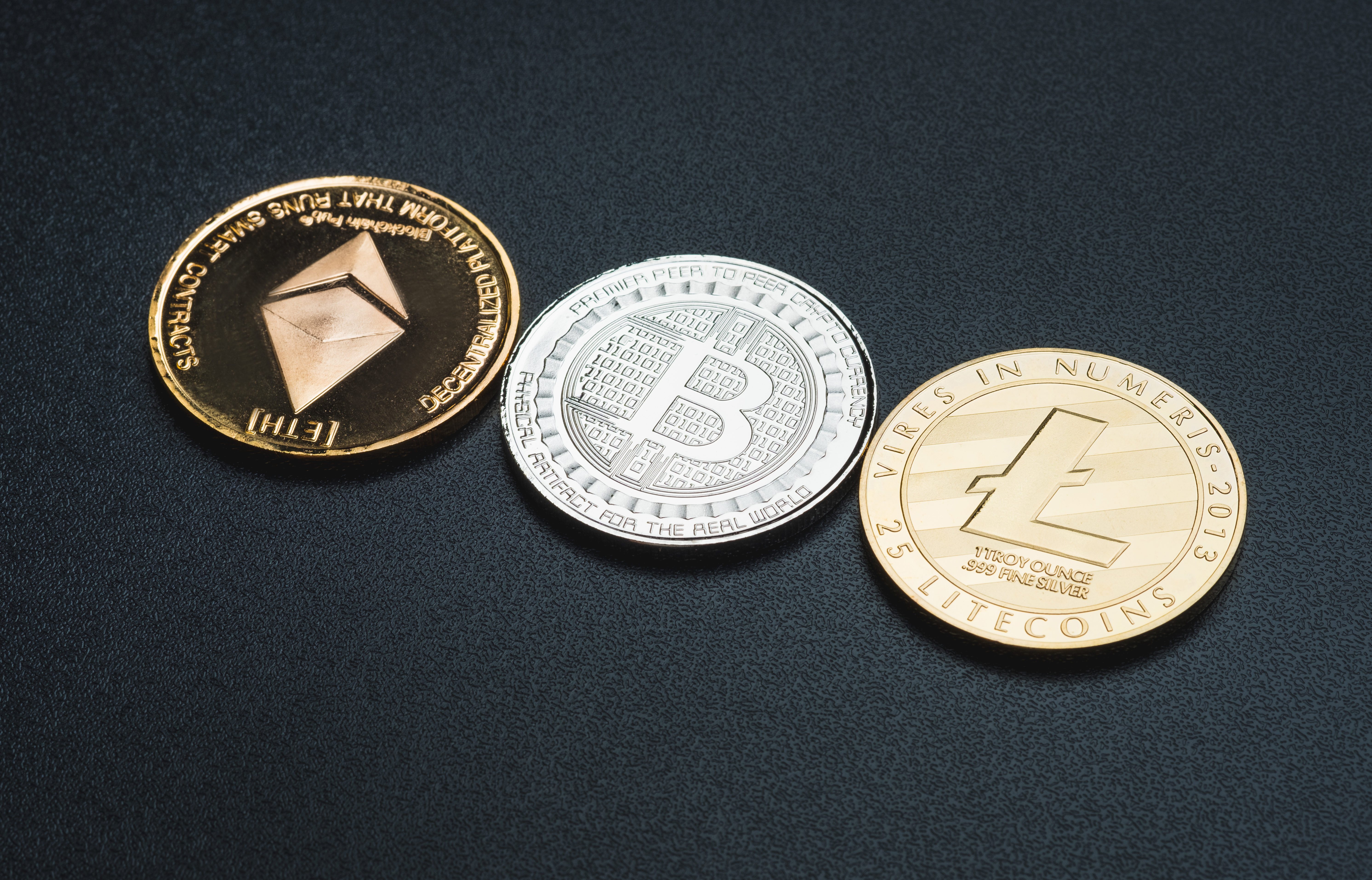 Cryptocurrency litecoin,Silver Bitcoin,Ethereum on black rough b